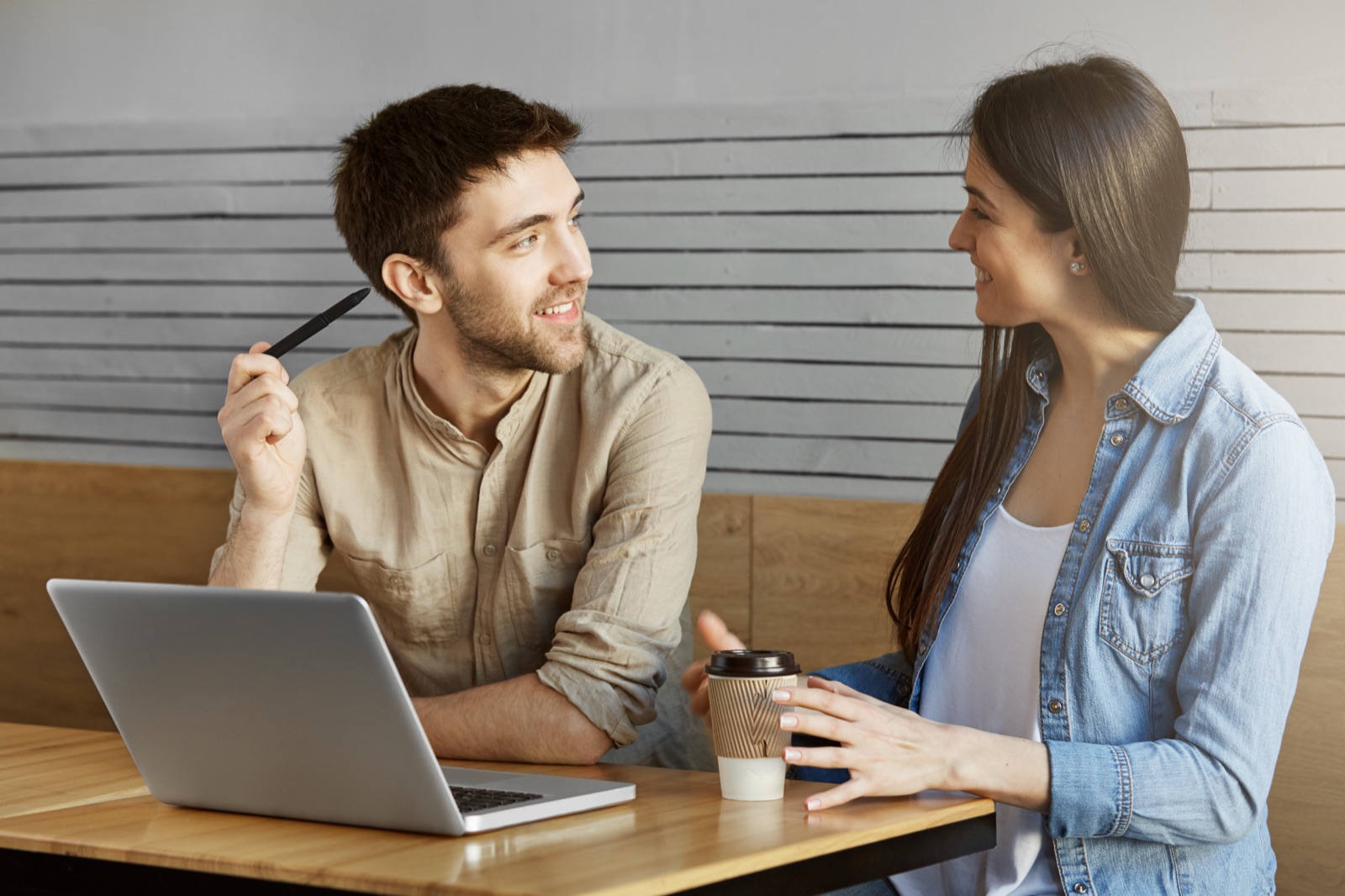 Dois profissionais conversando num café, um deles mostrando um projeto no notebook
